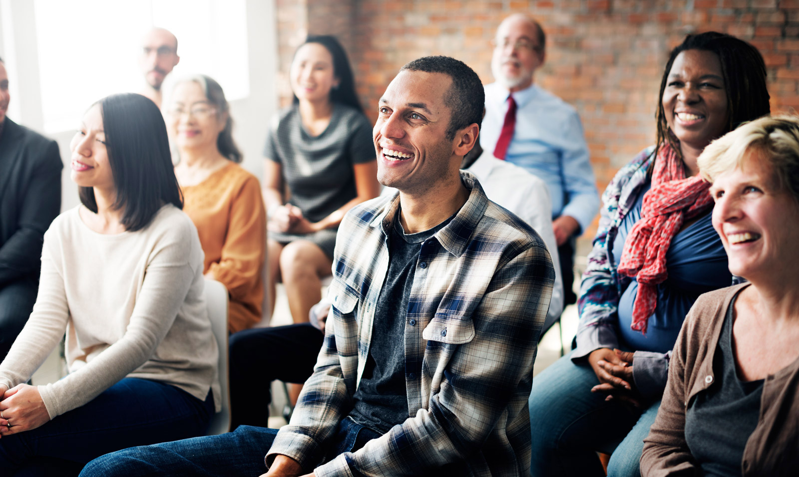 image of large group of people listening to speaker all smiling